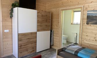 A cozy room with wooden paneling and modern furniture. The room is bright and features a bathroom as well as a television.