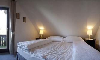 A cozy bedroom with a large double bed and soft lighting. The balcony offers a view outside.