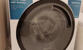 A washing machine with an integrated dryer from Bosch. It features the AutoDry function and is located in a modern bathroom.