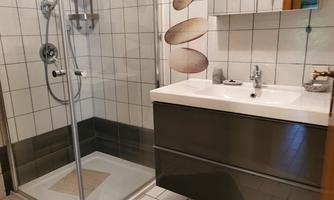 A modern bathroom with a glass shower and an elegant vanity. The walls are tiled, and the atmosphere feels clean and inviting.