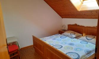 A cozy bedroom with a double bed and wooden furniture. The skylight lets in plenty of light and creates a friendly atmosphere.