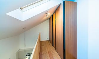 A modern hallway with wooden flooring and large cabinets. A skylight provides plenty of daylight.