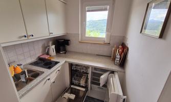 A small kitchen with modern appliances and a window that offers a view of the landscape. The countertop is bright and tidy.