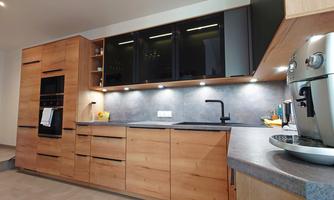 A modern kitchen with wooden cabinets and a light countertop. The equipment includes a sink and a modern coffee machine.
