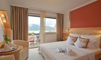 A cozy hotel room with a large bed and modern furniture. The window offers a beautiful view of the mountains.