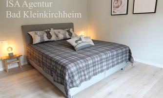 A cozy bedroom with a large double bed and an inviting throw. Decorative pictures hang on the wall, and there is a modern bedside lamp.