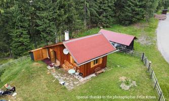 A cozy wooden house surrounded by trees on a meadow. There is a small garden and a quiet, nature-friendly atmosphere.