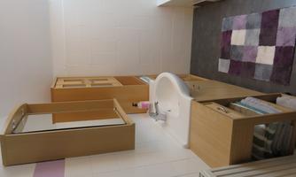 A modern bathroom with a sink, a mirror, and a bathtub. The floor is decorated with a colorful rug in purple and gray.