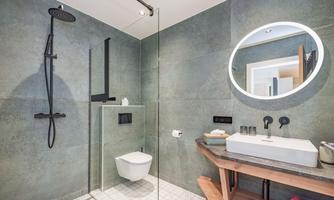 A modern bathroom with a clear shower area and elegant fixtures. The sink is placed on a stylish wooden shelf.