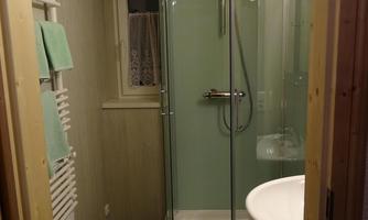 A modern bathroom with a shower and a sink. The walls are light, and the decoration is simple and functional.