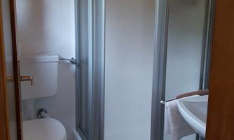 A modern bathroom with a shower, toilet, and sink. The walls are bright and the floor is tiled.