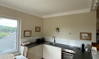 A modern kitchen with elegant design and colorful carpet. A table with chairs and large windows provide plenty of light.
