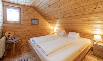 A cozy bedroom with wood paneling and a skylight. There is a double bed, bedside tables, and a picture on the wall.