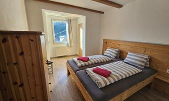 A cozy bedroom with two single beds and wood look. The window offers a view outside and brings plenty of daylight into the room.