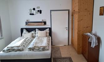 A cozy bedroom with a double bed and bright furniture. The walls are painted in soft colors and the floor is made of wood.