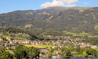 A picturesque landscape with mountains and a tranquil lake. In the foreground are houses and trees that create an idyllic atmosphere.