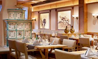A cozy restaurant with wooden furniture and elegant table settings. Artistic pictures hang on the walls, creating an inviting atmosphere.