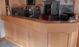 A modern kitchen with a wood block and a cooking island. There are several appliances and a cozy atmosphere.