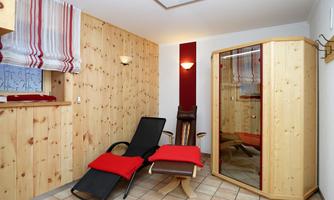 A cozy wellness area with wooden paneling. A deck chair and a sauna create a relaxing atmosphere.