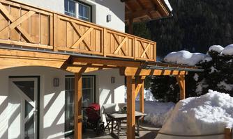 A modern house with a wooden balcony in a snowy landscape. The terrace offers a view of the mountains and is ideal for relaxing days.