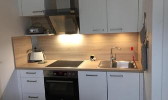 Modern kitchen with white cabinets and wood surfaces. Equipped with stove, sink, and kitchen appliances.