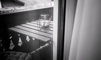 A table on a balcony with a lantern in a nostalgic style. The scene is in black and white and conveys a calm atmosphere.