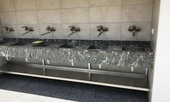 A sink area with multiple faucets. The surface is made of green marble material and is clean and modern.