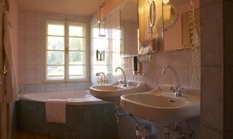 A modern bathroom with a large whirlpool and two sinks. The walls are bright and there is a window with a view of the outdoors.