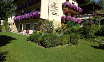 A pretty building with colorful flowers on the balcony. The well-maintained garden and the green lawn invite you to relax.