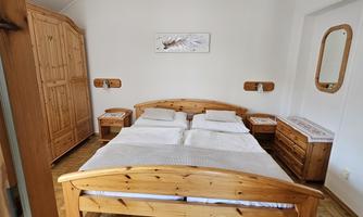 A cozy bedroom with a large wooden bed and a wardrobe. The walls are light, and the room feels inviting.