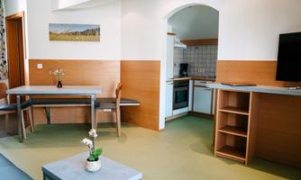 A modern apartment with a dining area and an open kitchen. The space is bright and cheerfully furnished.