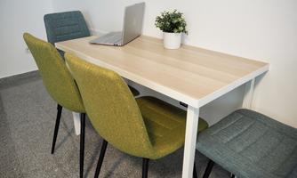 A simple table with two colorful chairs and a laptop. On the table, there is a small pot with a plant.
