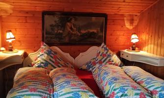 A cozy bedroom with a wooden wall panel and a large bed.  
Colorful cushions and soft lighting create an inviting atmosphere.