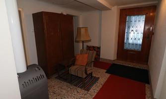 An inviting entrance area with a chair, a lamp, and a wardrobe. The floor is covered with carpets in various colors.