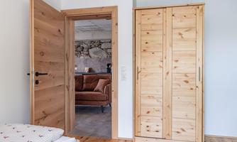 A bright room with an open door and a wooden wardrobe. In the background, a cozy sofa is visible.