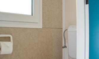 A modern bathroom with a white toilet and a window. The walls are painted in neutral tones.