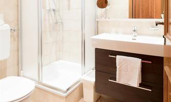 A modern bathroom with a glass shower and a sink on a wooden cabinet. The walls are painted in light colors, creating a friendly atmosphere.
