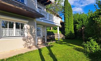 A beautiful house with a well-maintained garden and plenty of greenery. The sun is shining and there is a terrace for relaxing.