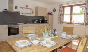 A bright and modern kitchen with a dining table set for a meal. The rooms are designed to be friendly and inviting.