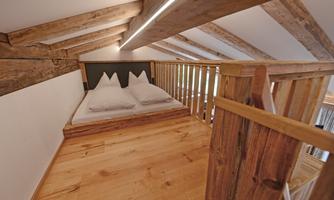 A cozy bedroom in the attic with wooden planks and a double bed. The natural materials create a warm atmosphere.