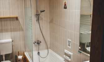 A modern bathroom with a bathtub and shower. Wooden details and elegant fixtures create a cozy atmosphere.