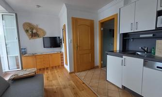 A bright apartment with modern design and wooden flooring. The kitchen is functional and there is a cozy seating area.
