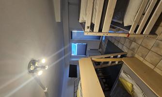 A simple room with two bunk beds and a window. The room is bright and neatly furnished.