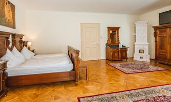 A cozy bedroom with a large wooden bed and traditional furniture. The room features a warm, inviting floor and elegant decor.