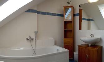 A modern bathroom with a bathtub and a sink. Bright walls and a Velux window provide plenty of light.
