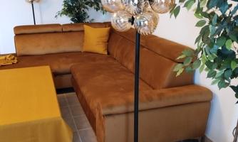 A cozy living room with a brown couch and an elegant table. In the background, there are green plants and a striking floor lamp.