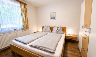 A cozy bedroom with a large double bed. The bright walls and wooden interior create a pleasant atmosphere.