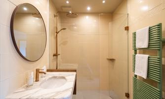 A modern bathroom with a walk-in shower and a beautiful mirror. Skincare products are on the sink, and fresh towels are ready.