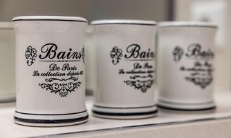Three decorative toothbrush holders with elegant embellishments. They are standing side by side on a smooth surface.
