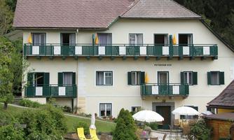 A charming guesthouse with several balconies and green shutters. The outdoor area is equipped with umbrellas and sun loungers to enjoy relaxing hours outdoors.